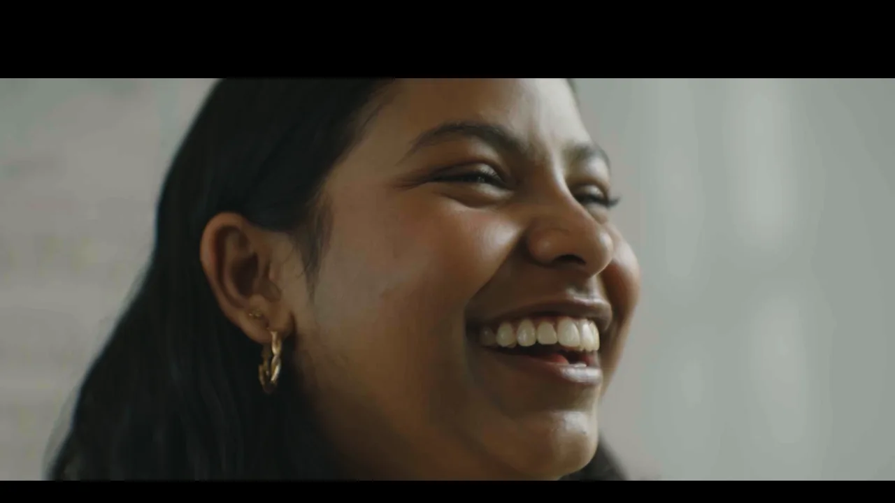 A woman smiles in a human-centered documentary scene